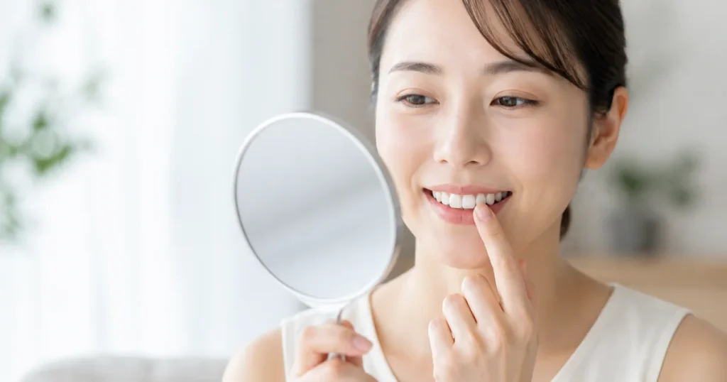 歯の表面に見える白い斑点を鏡で確認する女性